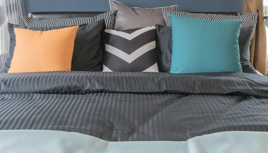 colorful pillows on dark color bed in modern bedroom